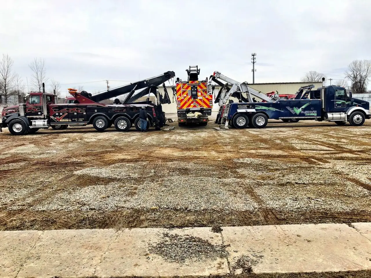 Three Wilson's Towing wreckers and a rotator parked at the yard