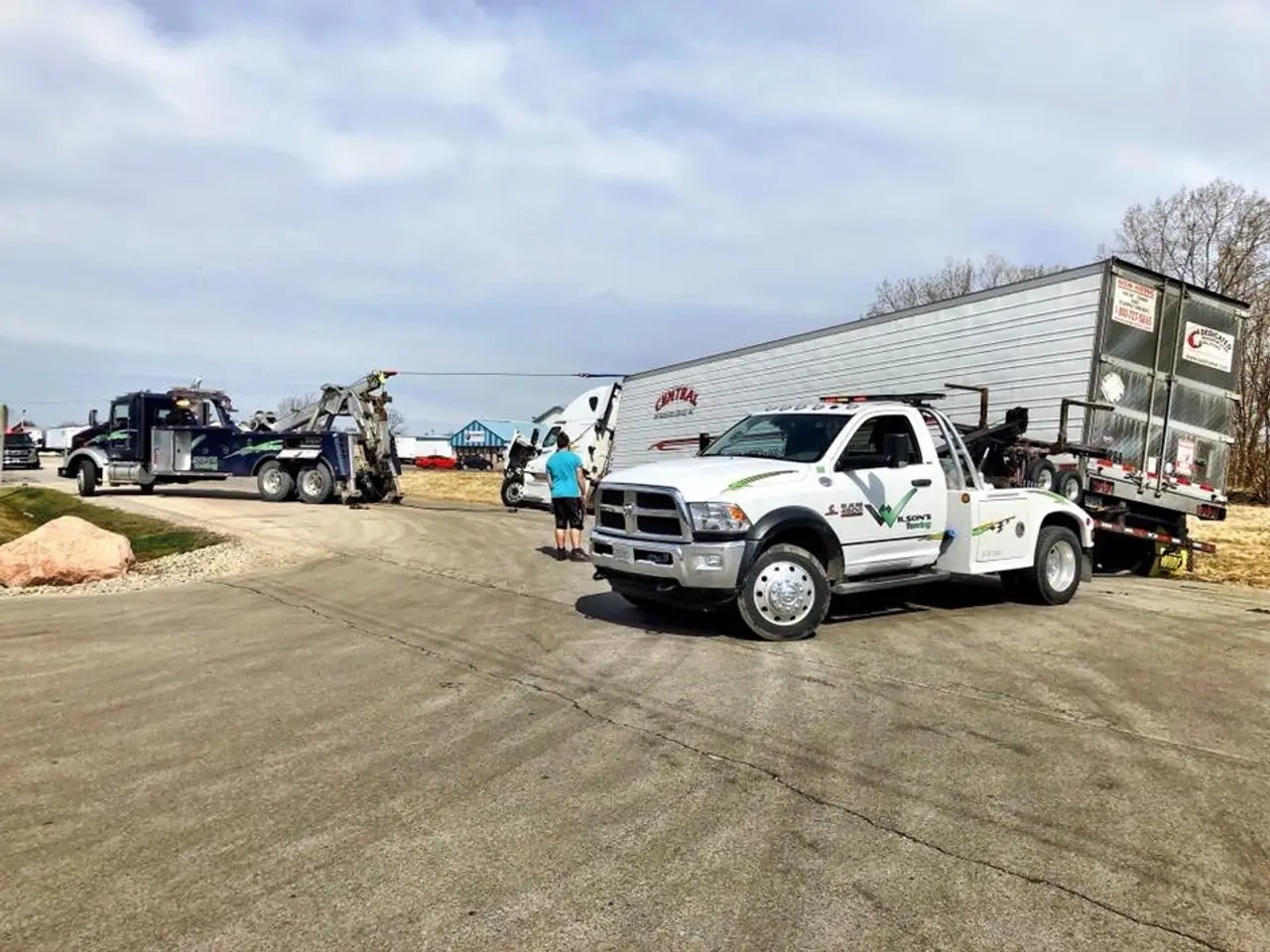 A light-duty Wilson's Towing wrecker with a trailer hooked up at the yard