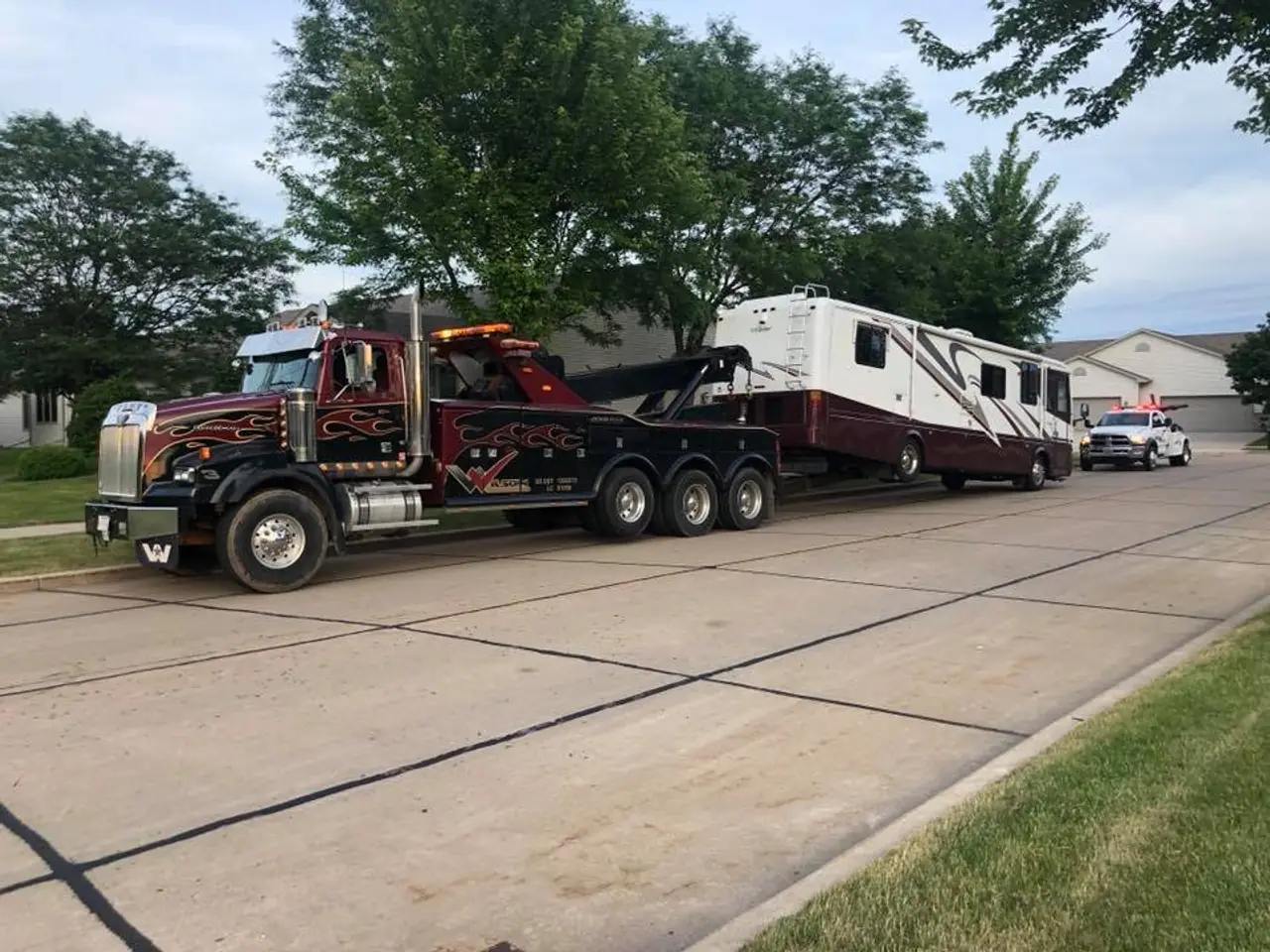 A Wilson's Towing heavy wrecker towing a motorhome down a residential street